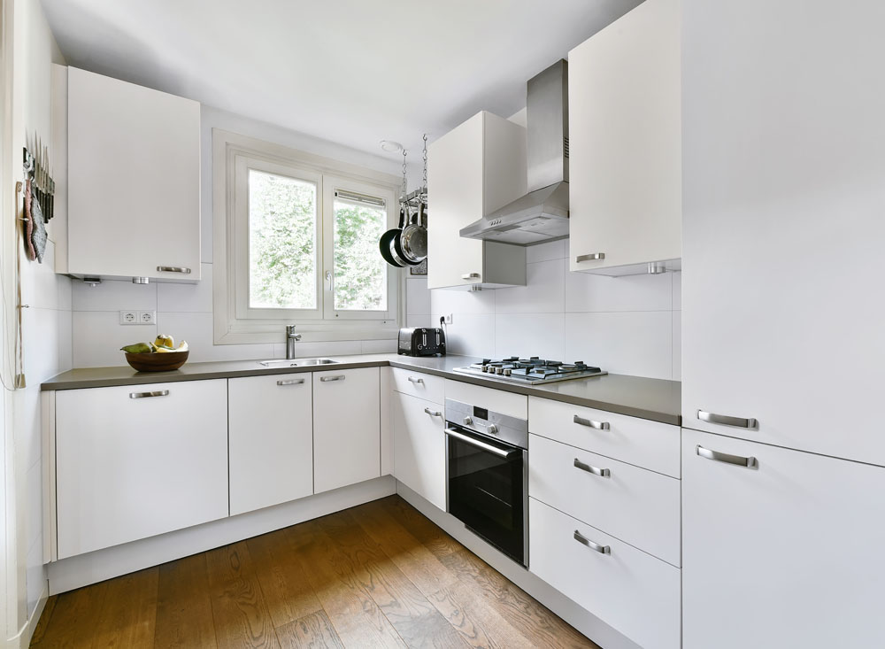 Modern white kitchen cabinets with a sleek countertop and stainless steel appliances – custom cabinetry for home remodeling.